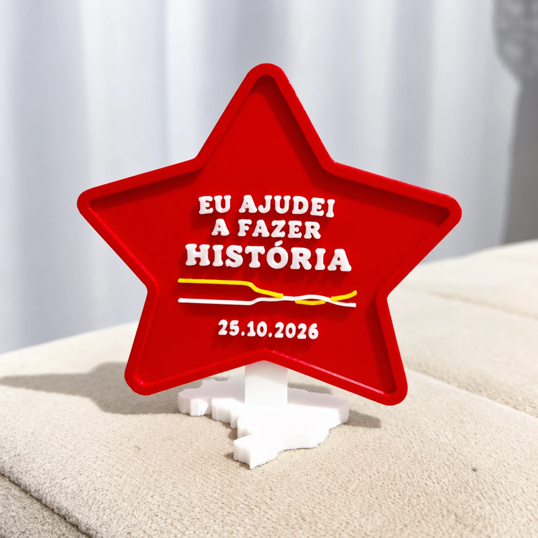 Troféu original impresso em 3D: estrela vermelha com a frase Eu ajudei a fazer história e base branca em formato do Brasil